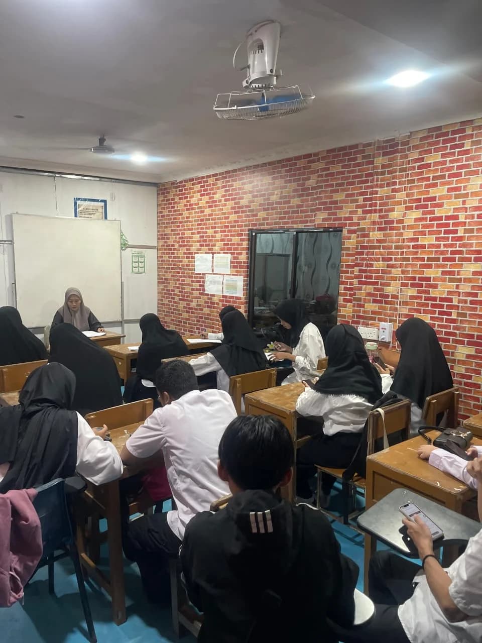 Tutor mendampingi peserta yang sedang belajar di ruang kelas