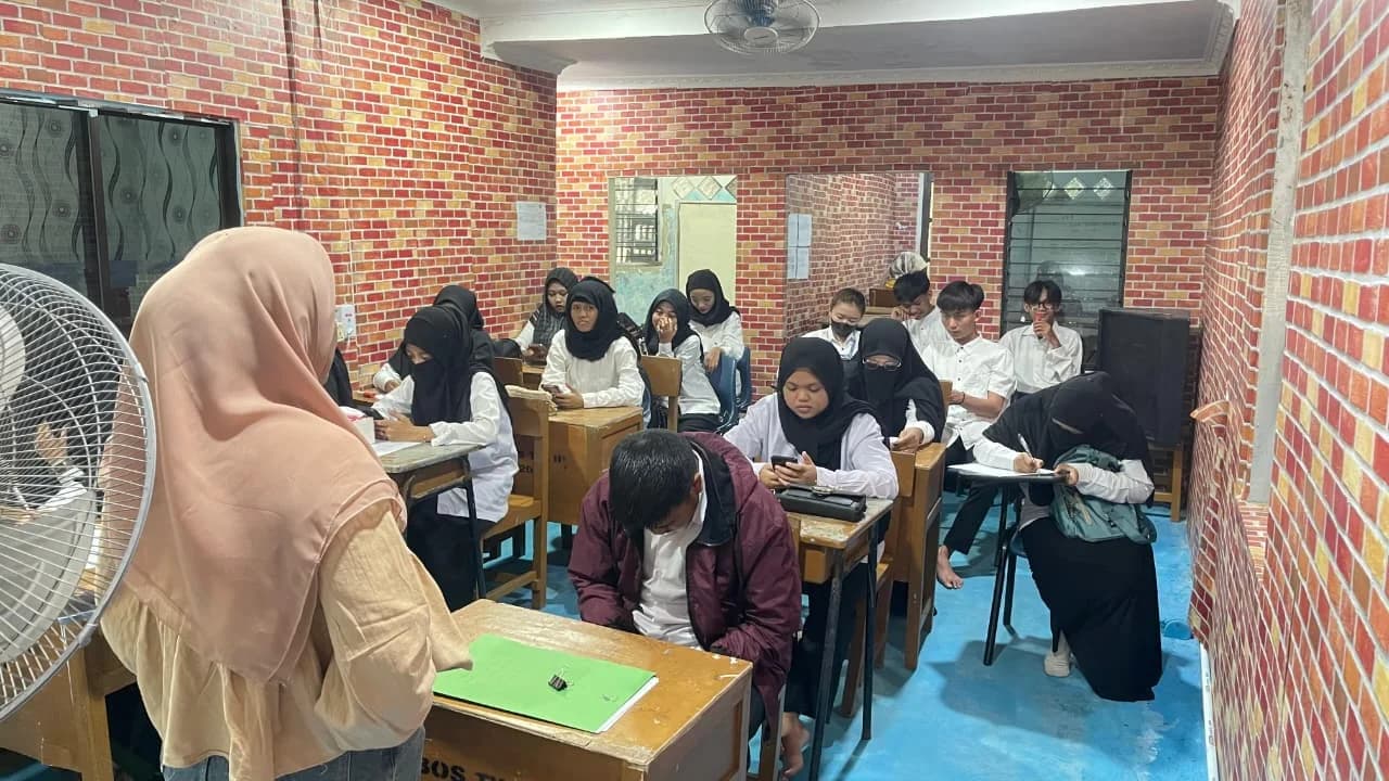 Guru mendampingi peserta yang sedang belajar di kelas berdinding bata